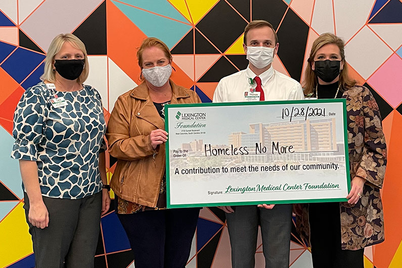 Homeless No More representatives, wearing masks, are presented an oversized check from the Lexington Medical Center Foundation, for contributions to meet the need of our community.