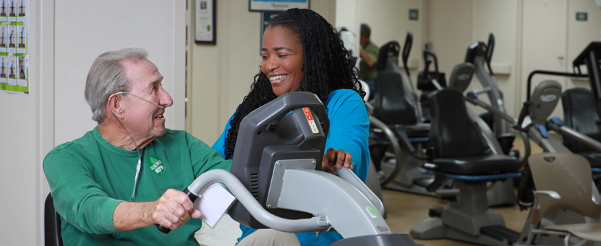 A patient smiles as a therapist evaluates his exercise.